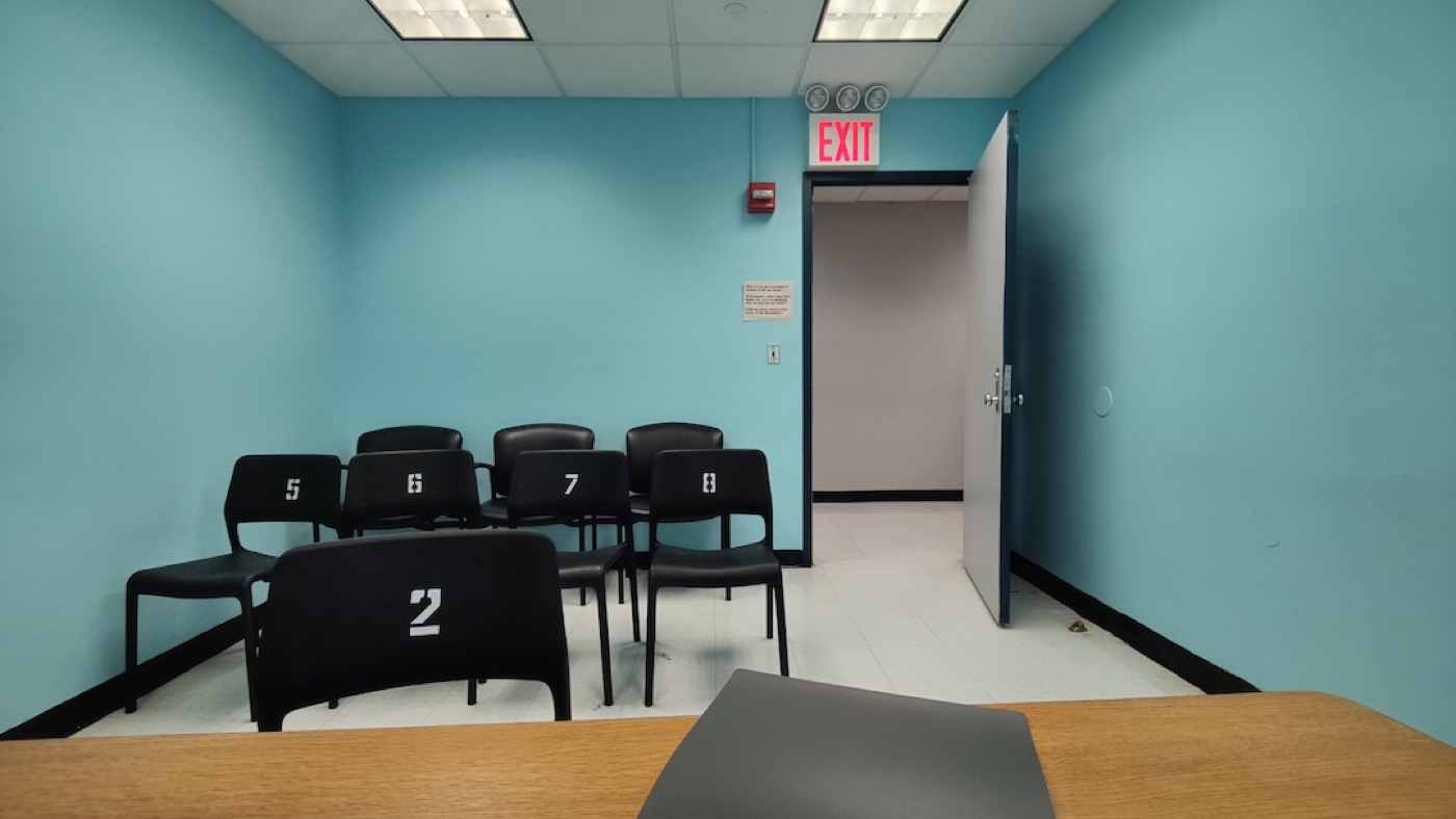Numbered black chairs arranged in a teal-walled small claims courtroom.